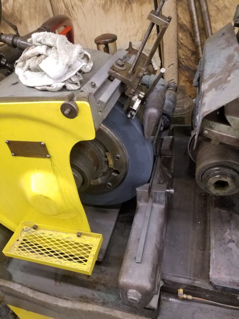 Various mechanical parts and a yellow guard cover in a workshop.