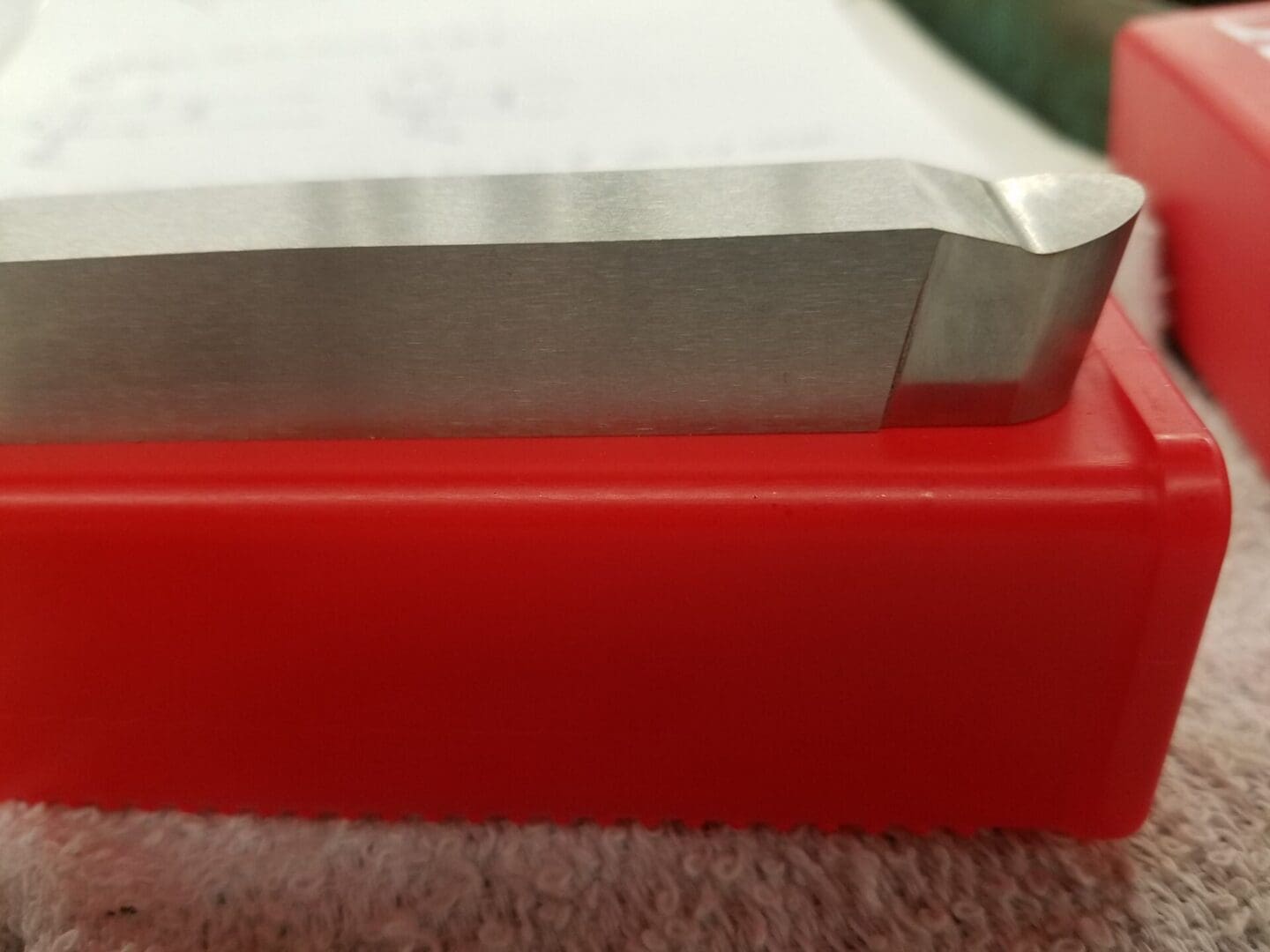 Close-up of a white book or notebook on a red surface.